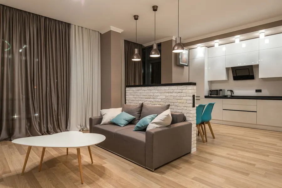 Wohnbereich mit Sofa, Couchtisch und offener Küche in einer möblierten Wohnung
