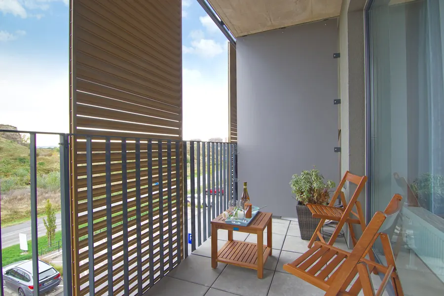 Balkon einer Ferienwohnung mit Holzmöbeln und Blick ins Grüne