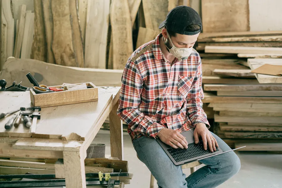 Craftsman in a workshop working at a laptop
