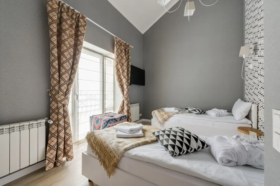 Zimmer mit zwei Betten, frischen Handtüchern und Fenster zum Balkon
