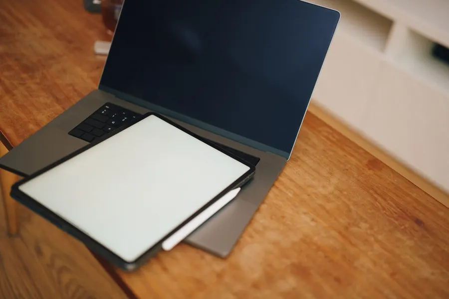 Aufgeklappter Laptop mit Tablet auf einem Holztisch